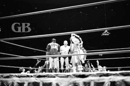 Ray Stevens, Don Chuy (back to camera), and Wahoo McDaniel go over match strategy as eager fans beg for autographs.