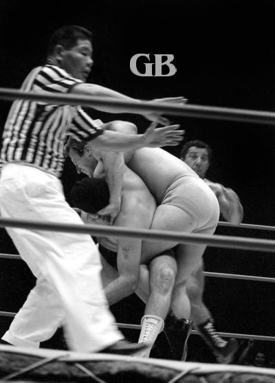 Referee Wally Tsutsumi tries to keep Enforcer #2 from interfering with the match as his partner Enforcer #1 suffers in Bockwinkel's famous Abdominal Stretch.