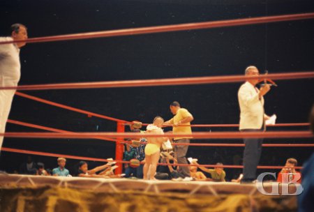 Ring announcer Jim Lathrop introduces the next match as Little Beaver signs autographs in the background
